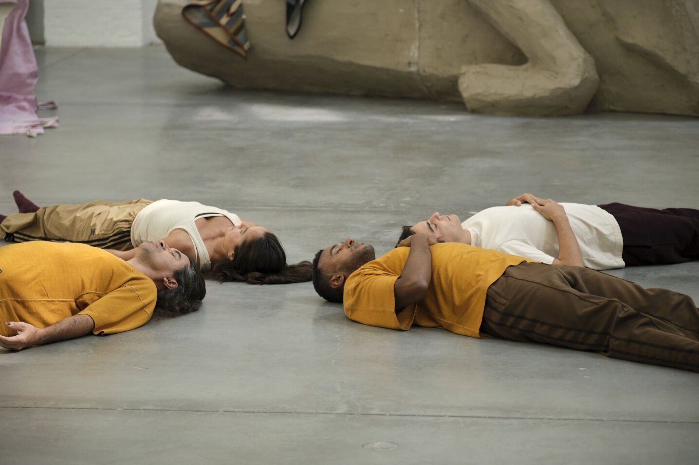 Four dancers lay on the ground with their heads together